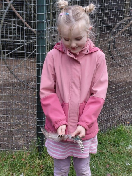 M&auml;dchen in rosa zeigt gesammelte Federn