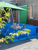 Schwimmbecken mit Kindern vor Haus Grün
