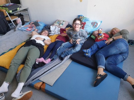 Schüler und Lehrer liegen und sitzen auf einem Matratzenlager