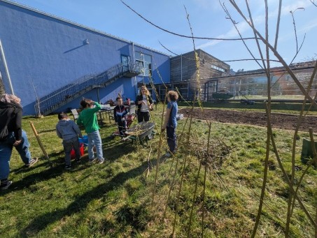 Sch&uuml;lergruppe von Hinten steht um ein Beet