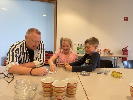 Schulleiter spielt mit Schülerin und Schüler Karten