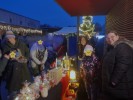 Mehrere Personen warm gekleidet am Weihnachtsmarktstand. Im Hintergrund Weihnachtsbeleuchtung