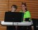 Schüler und Lehrer sitzen gemeinsam hinter dem Keyboard.