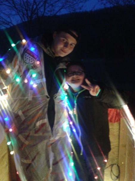 zwei Jungen, mit Lichterketten beleuchtet, halten sich im Arm