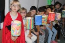 Schülerinnen und Schüler sitzen in einer Reihe und halten ihre Laternen