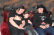 eine Frau und 2 Jungs sitzen auf einem roten Sofa. Alle tragen die schwarzen Schulband Shirts. 