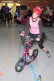 Mädchen mit roten Helm und pinken Shirt auf Roller